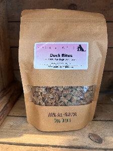 Bag of Hugs & Otis Duck Bites dog treats on a wooden surface