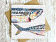 Card with a colorful fish illustration on a wooden surface
