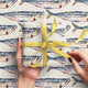 Gift wrapped in colorful fish-patterned paper with a yellow ribbon on a matching background.