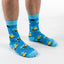 Blue socks with yellow bee patterns worn by a person on a white background