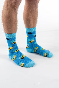 Blue socks with yellow bee patterns worn by a person on a white background