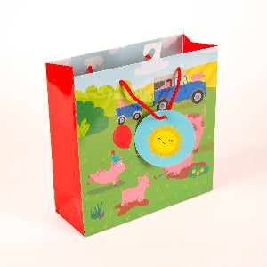Children's gift bag with farm animal design and red handle on a white background